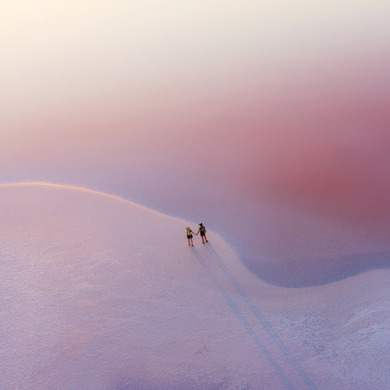 A couple of people holding hands, standing on an icy and snowy ground. 
